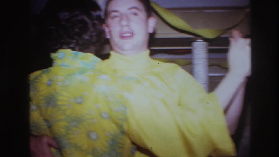 The young man smiles toward the camera while dancing with his mother beneath streamers in the 1967 Ottawa birthday setting.