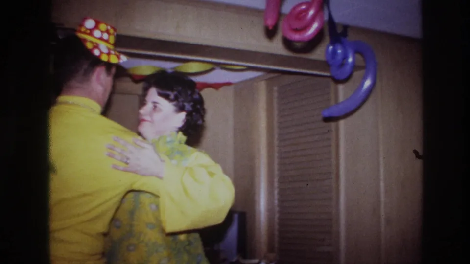 Ottawa 1967 home-movie frame showing the couple swaying together, with the woman facing the camera and party decorations overhead.