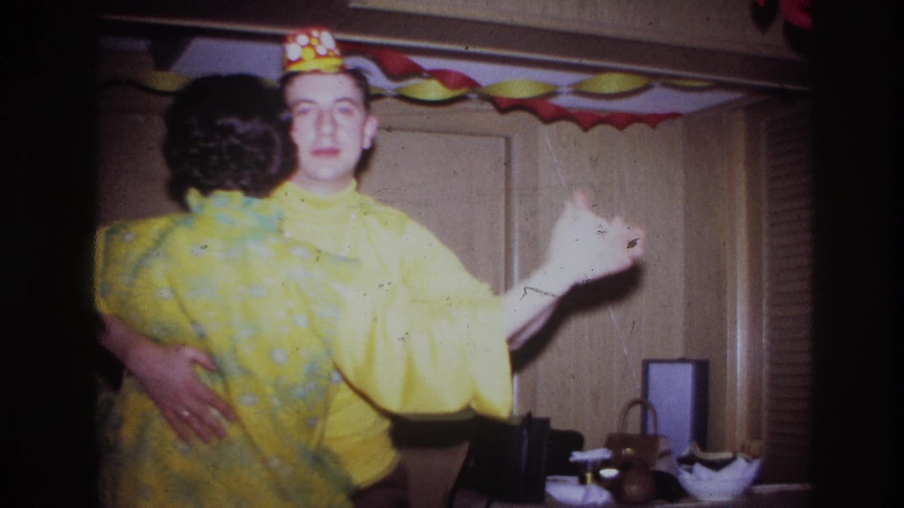 1967 Ottawa home-movie frame of a couple dancing at an indoor celebration, surrounded by colorful paper decorations and wood-paneled walls.