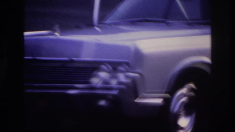 1967 Ottawa frame with a close, blurred view of the sedan's front quarter, hood, wheel, and chrome details behind window divisions.