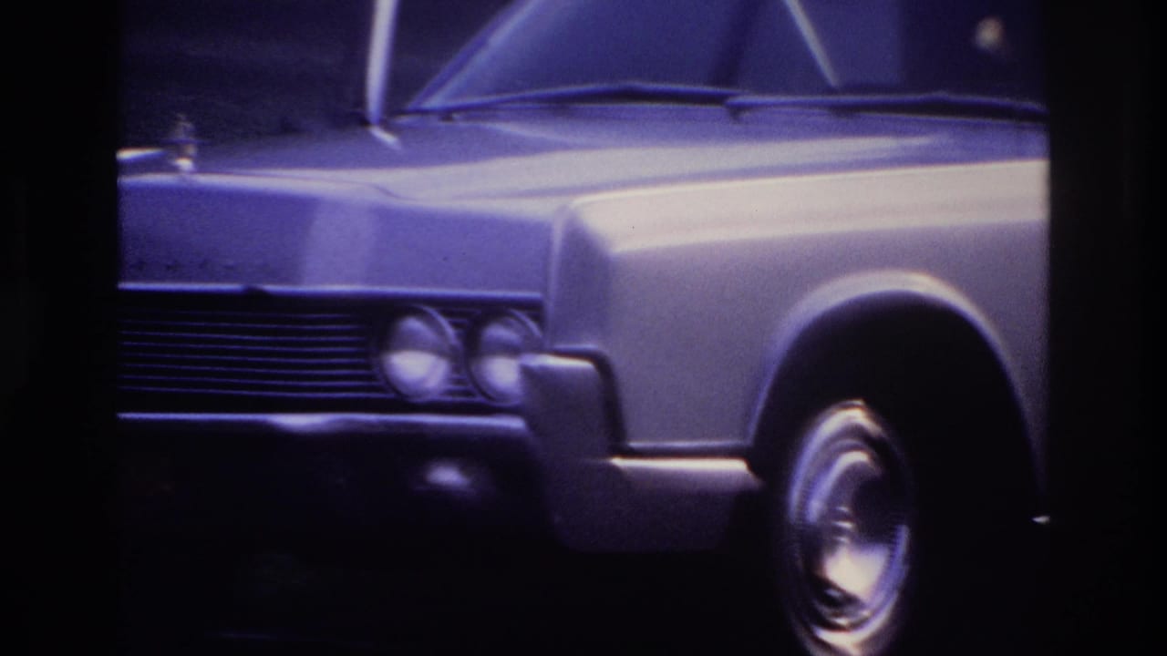 Close 1967 Ottawa home-movie view of a silver sedan with chrome trim and quad headlights beside a dark roadside area.