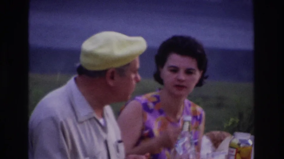 Soft 8mm frame from Ottawa in 1967 showing two adults in conversation at an outdoor picnic table.