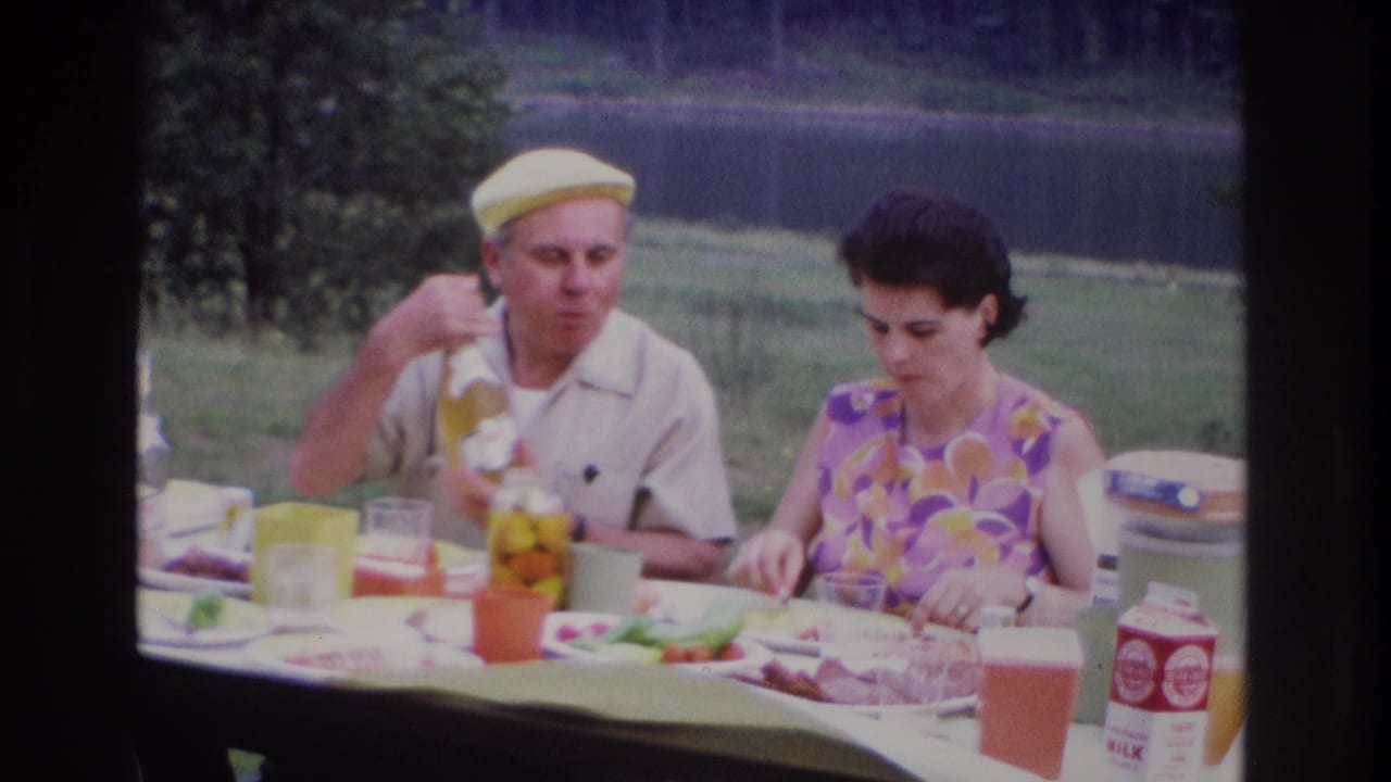 1967 Ottawa picnic scene showing a man pouring a drink from a bottle as a woman prepares or eats food at the table.
