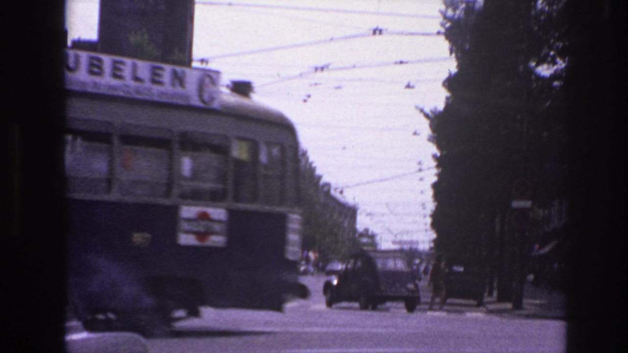 Rear section of a trolley or bus moving through an intersection beneath overhead wires.