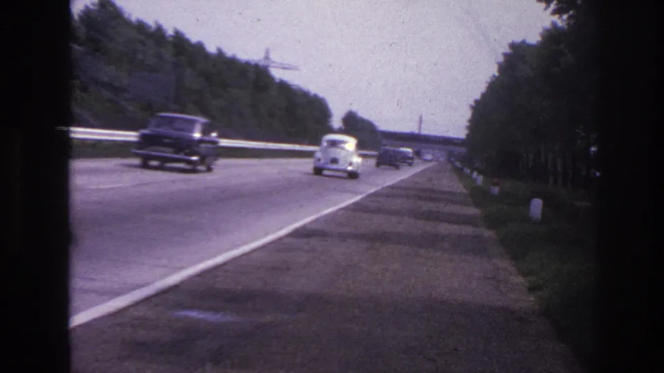 1967 Paris-area highway view with classic cars spaced across the lanes, seen through soft 8mm color footage.