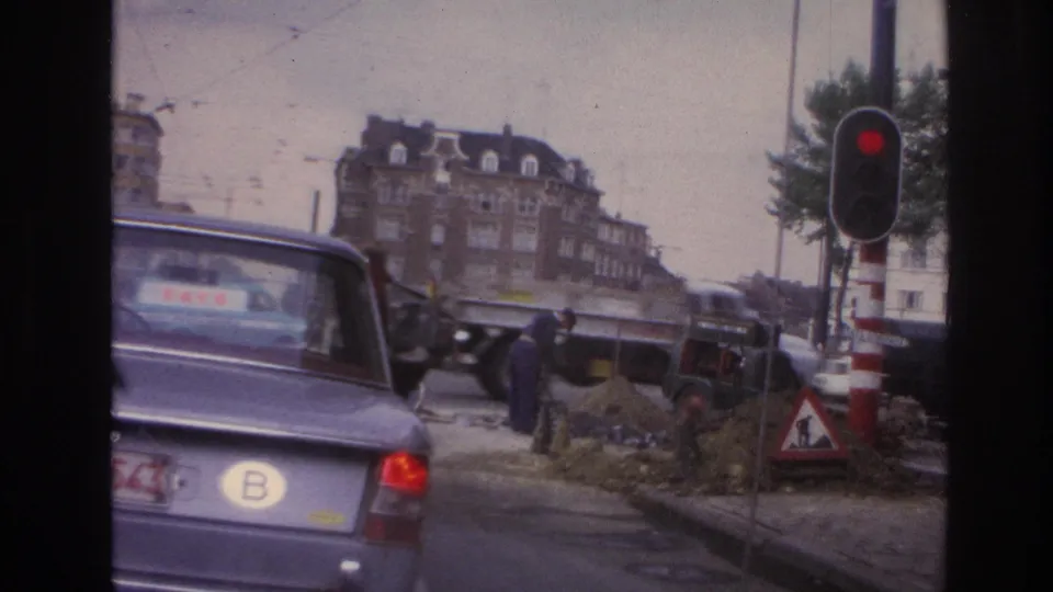 1967 Paris roadwork scene with a red traffic light, warning signs, workers, a truck, and cars moving through the intersection.
