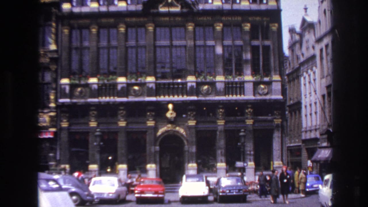 1967 Paris street view showing an ornate historic facade, parked period cars, and pedestrians near the entrance.