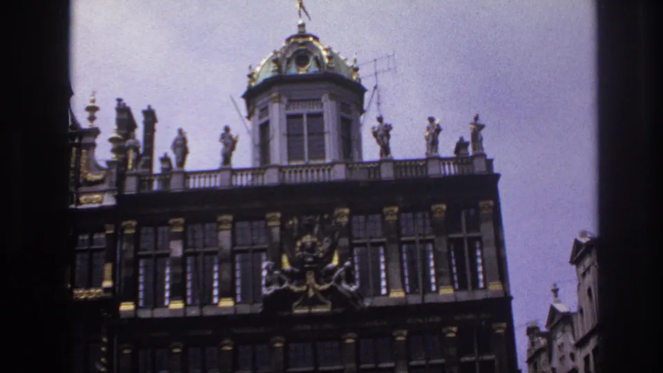 1967 Paris 8mm frame focused on the upper facade, showing the green dome, statues along the parapet, and dark architectural ornament.