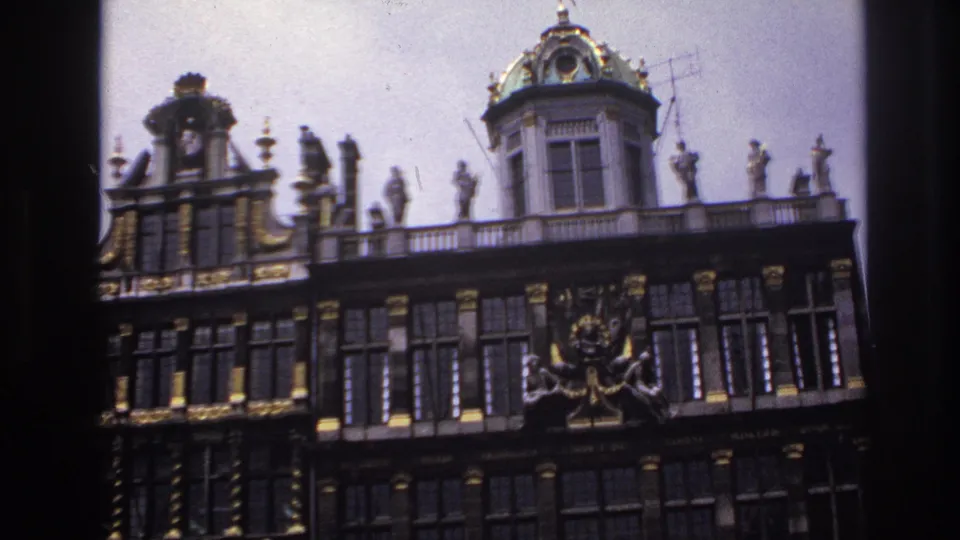 1967 Paris home-movie frame showing the decorated facade, green dome, rooftop figures, visible antenna, gilded details, and neighboring roofline.