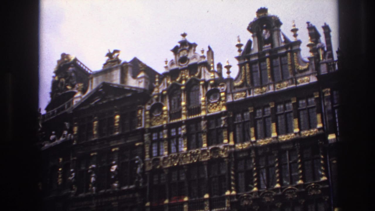 1967 France-linked 8mm frame showing an ornate European building facade, gilded roofline details, tall windows, and pale sky.