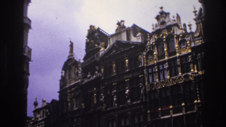 1967 France-linked 8mm frame showing ornate historic facades, tall windows, gilded trim, and a shaded foreground border.