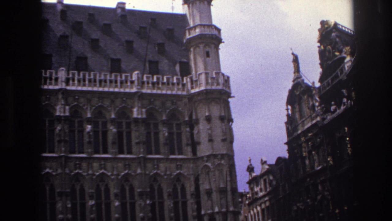 Crenellated stone facade and tower with a darker ornamented building at the right edge.