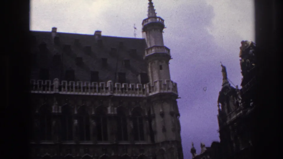 Soft, grainy 1967 Paris frame with a crenellated stone building, tower and darker adjacent historic facade in view.