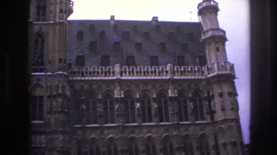 1967 Paris 8mm frame with a tall central tower, patterned roof, carved stone facade, and dark vertical frame at the left edge.