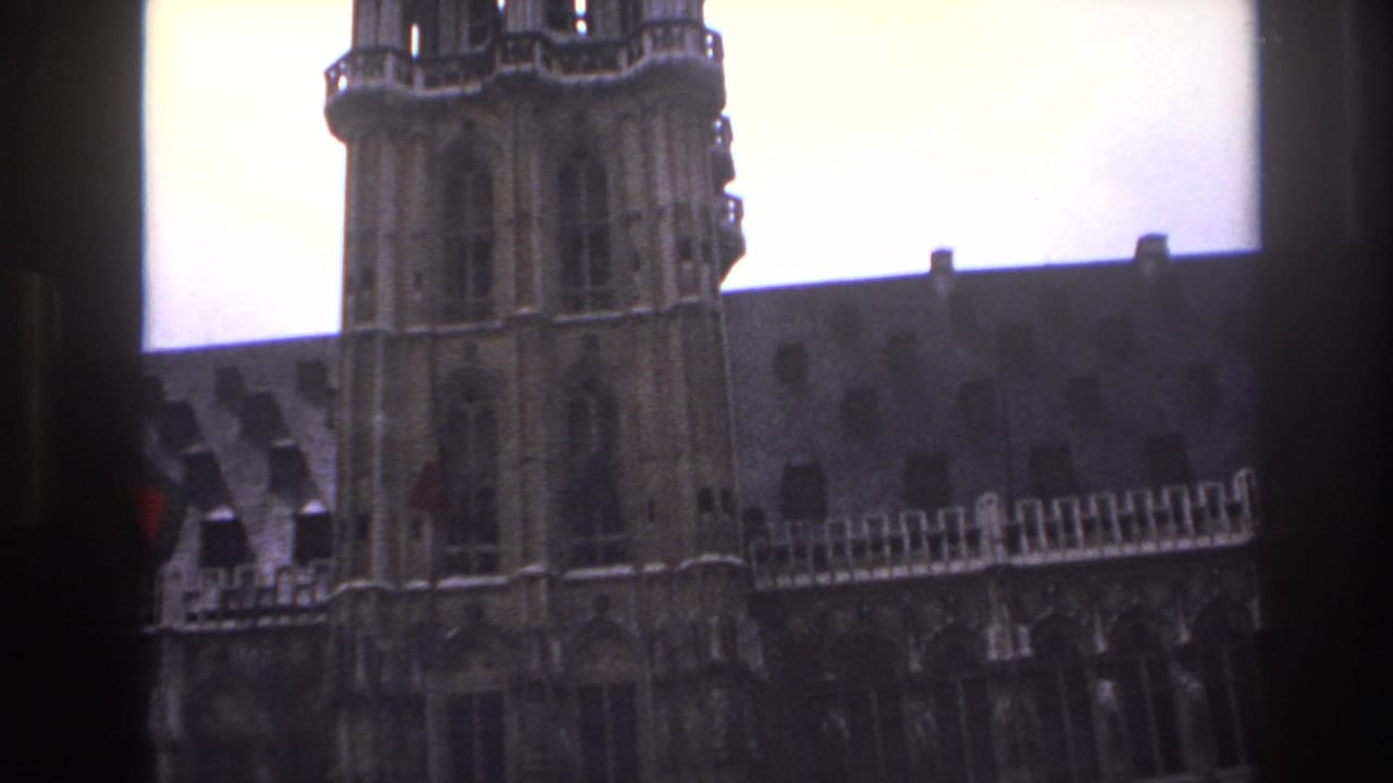 1967 Paris home-movie frame showing a low-angle view of a Gothic cathedral facade, twin towers, and steep roofline.