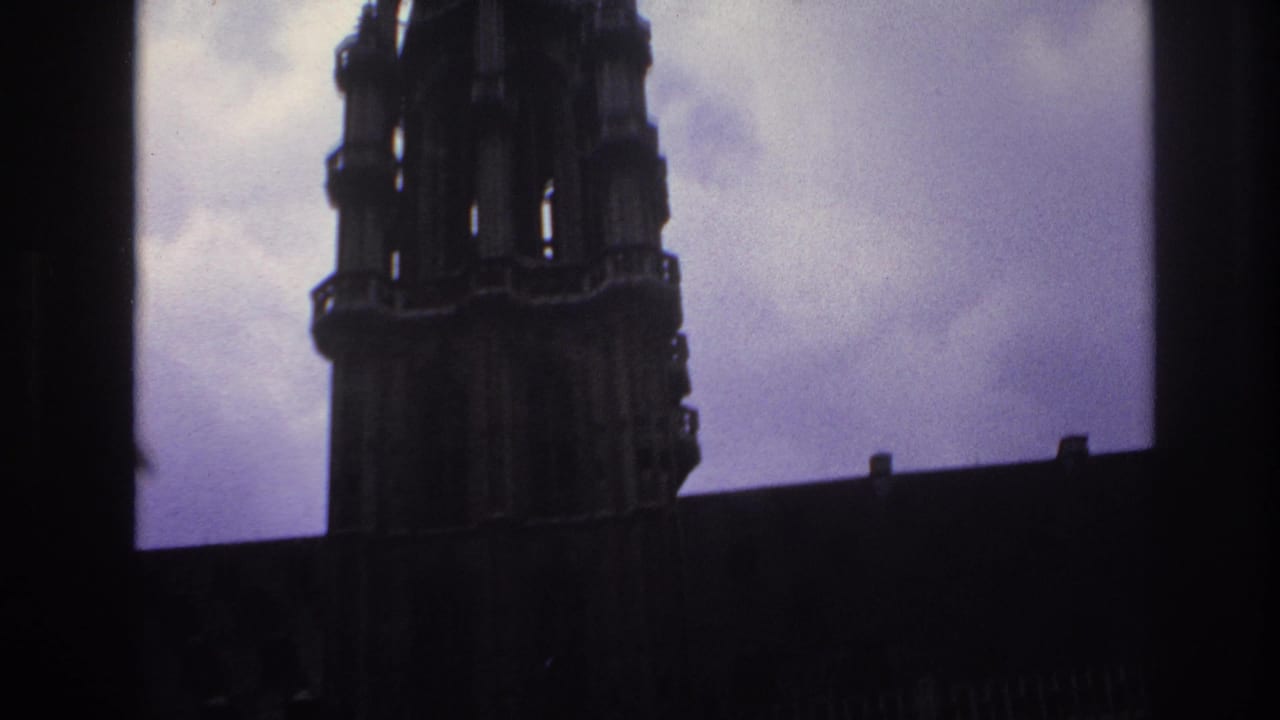 Dark cathedral tower and roofline silhouetted against a cloudy sky.