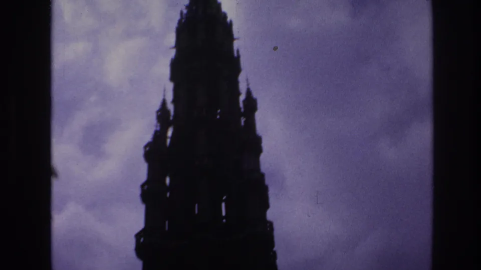 1967 Paris frame with the upper portion of a Gothic cathedral tower silhouetted against a clouded purple-blue sky.