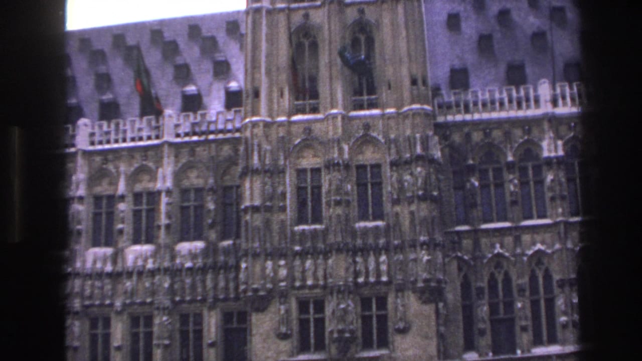 Ornate stone building facade with arched windows and a small flag near the roofline.
