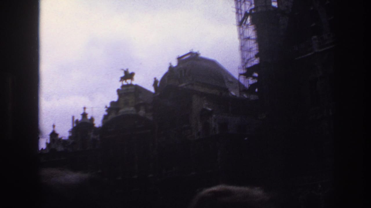 Shadowed domed rooftop with a small equestrian statue, scaffolding, cloudy sky, and crowd silhouettes at the bottom.