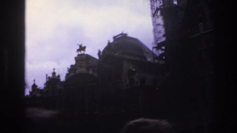 1967 Paris frame showing a dark roofline with a domed building, rooftop equestrian statue, scaffolding, and overcast sky.