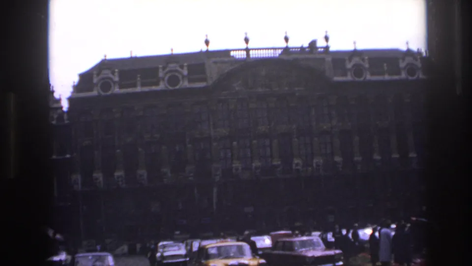 1967 Paris square with a large ornate building, rows of windows, and classic cars moving below the facade.