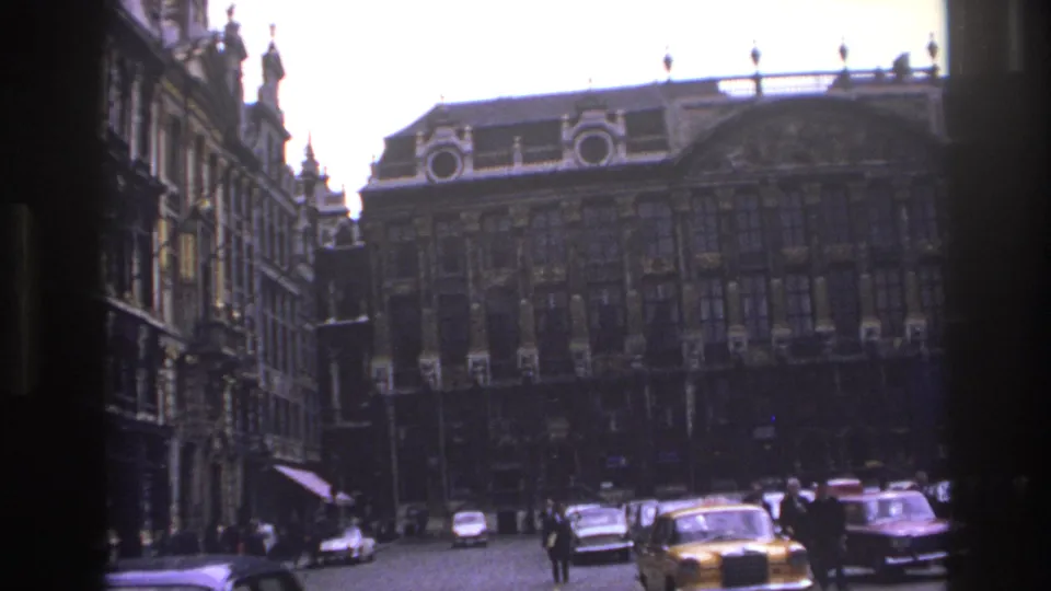 1967 Paris street-level frame showing classic cars, pedestrians, side facades, and an ornate historic building across the square.