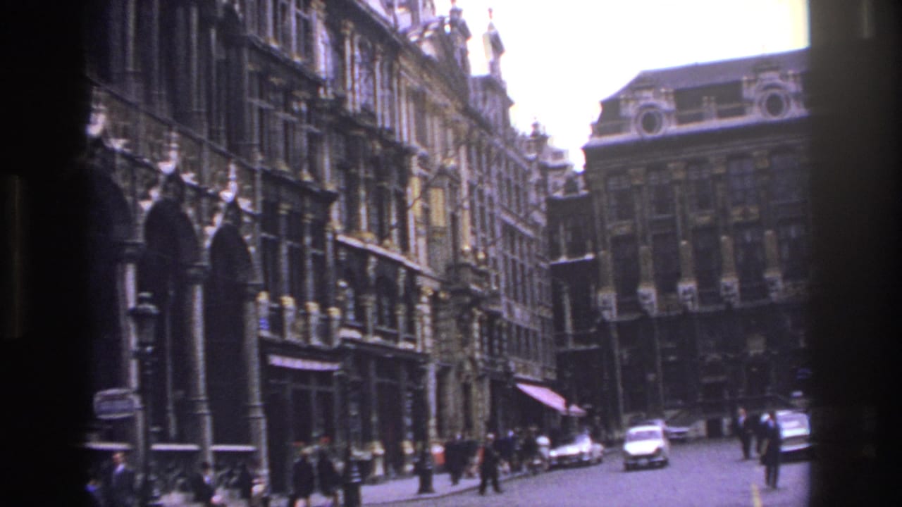 Historic street facades with pedestrians and cars partly obscured by a dark film edge.