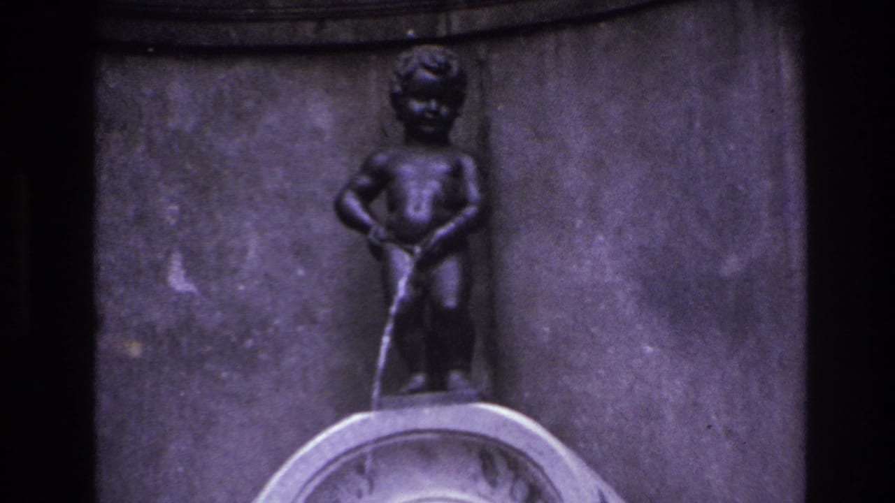 1967 8mm travel frame showing a small boy-like fountain statue with water flowing downward against a dark stone wall.