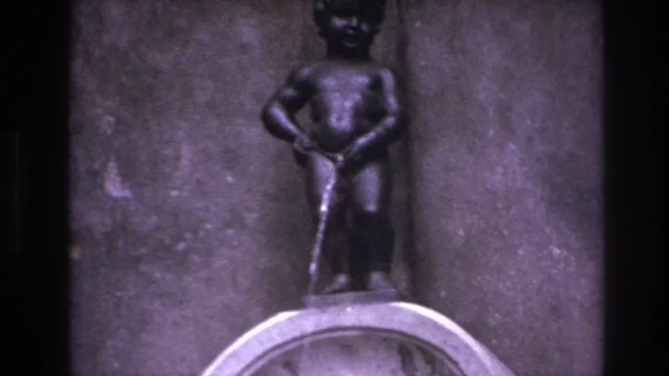 Close 1967 8mm travel view of the small fountain sculpture, showing the figure, water stream, and basin edge.