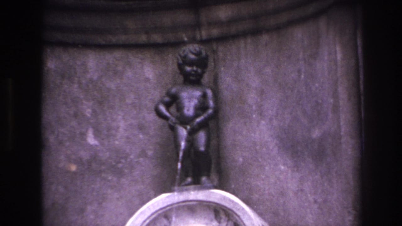 1967 8mm travel frame showing a close view of the small bronze fountain figure and pale basin against carved stonework.