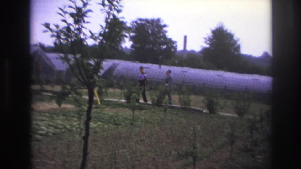 At the end of the clip, two men walk through the cultivated garden area in Paris, framed by dark edges and backed by the long arched greenhouse.