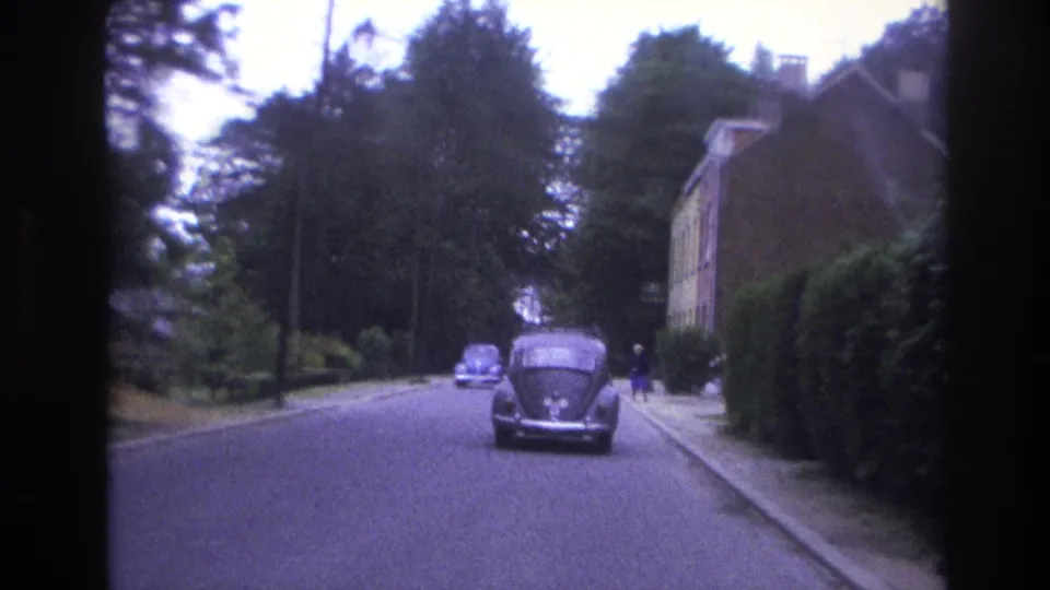 Later 1967 Paris frame with the Beetle ahead, another car in the distance, and a pedestrian briefly visible near the right sidewalk.