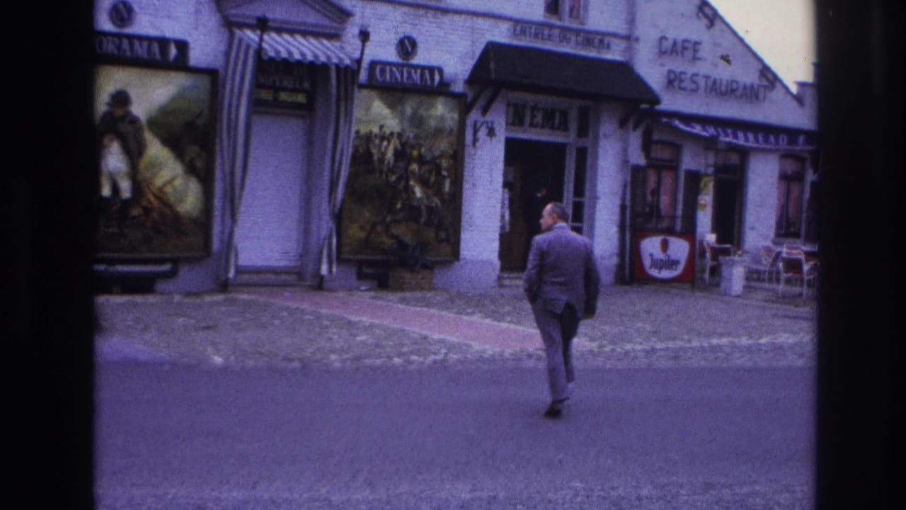 Man continues walking from the street toward the cinema doorway.