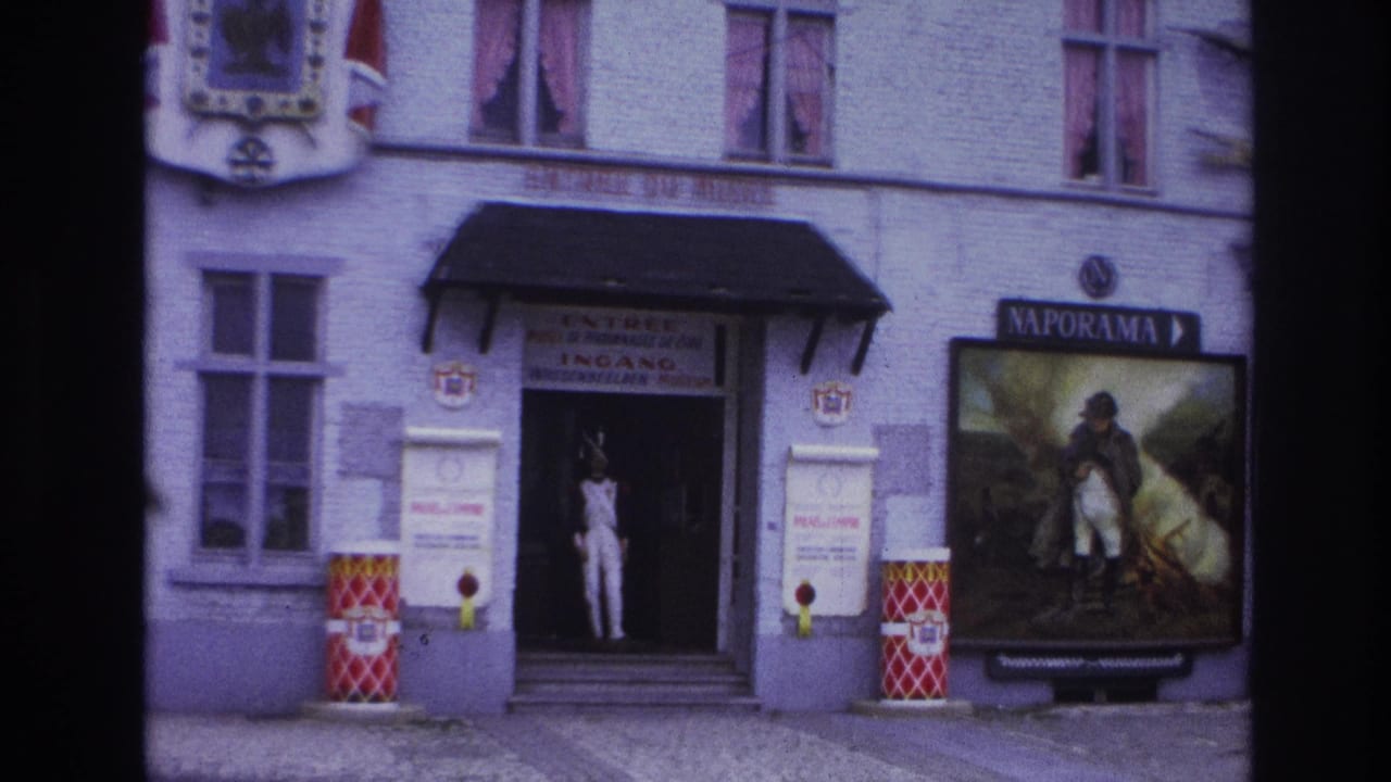 1967 Paris 8mm frame showing a museum entrance with a uniformed mannequin, Naporama Napoleon poster, facade windows, and French signage.