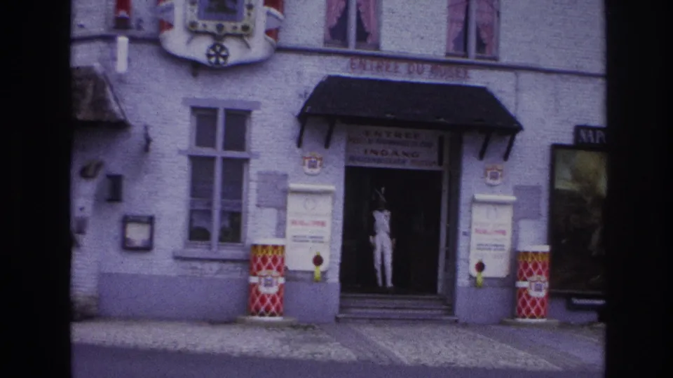 1967 Paris 8mm view of a light-colored museum facade with entrance signage, mannequin in the doorway, windows, and partial Naporama display.