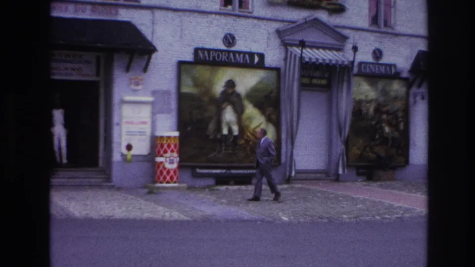 Paris, 1967, with a man walking past an open exhibit doorway, Naporama poster, and cinema signage.