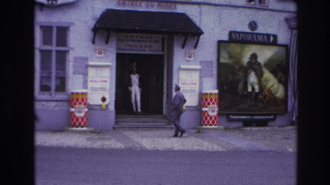 Man in a suit walking toward a museum doorway beside a Naporama poster.