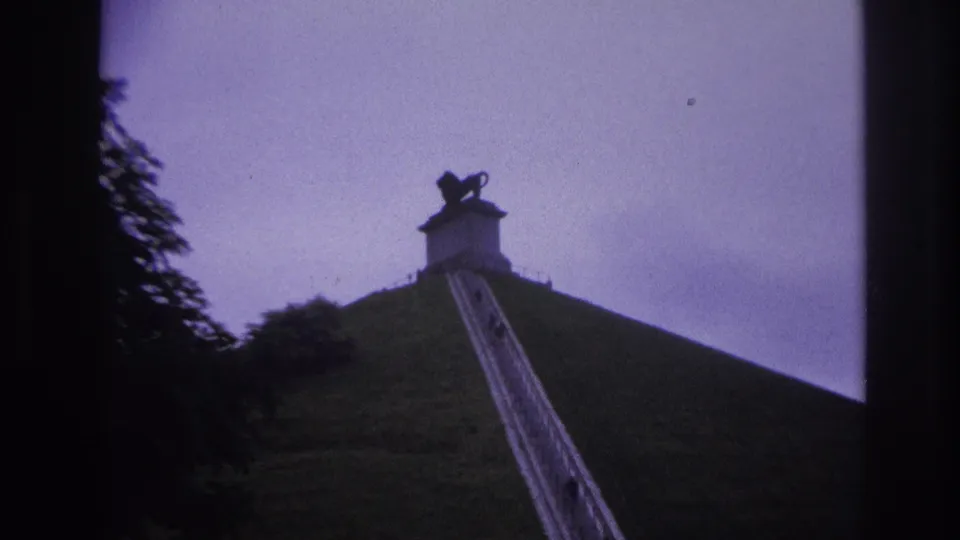 The final frame centers the lion statue silhouette above the mound, with the stairway and a few distant visitors below.
