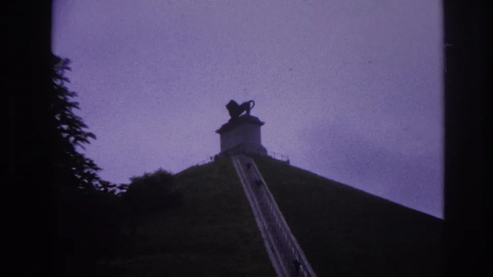 A low-angle 1967 Paris travel frame shows the stairway, railings, grassy slope, and lion statue silhouetted above.