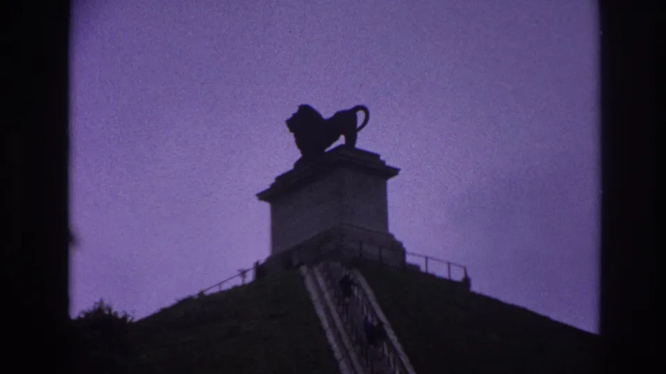 Final 1967 Paris frame with the lion statue prominent over the plinth, stairway, grass, railing, and purple-tinted sky.