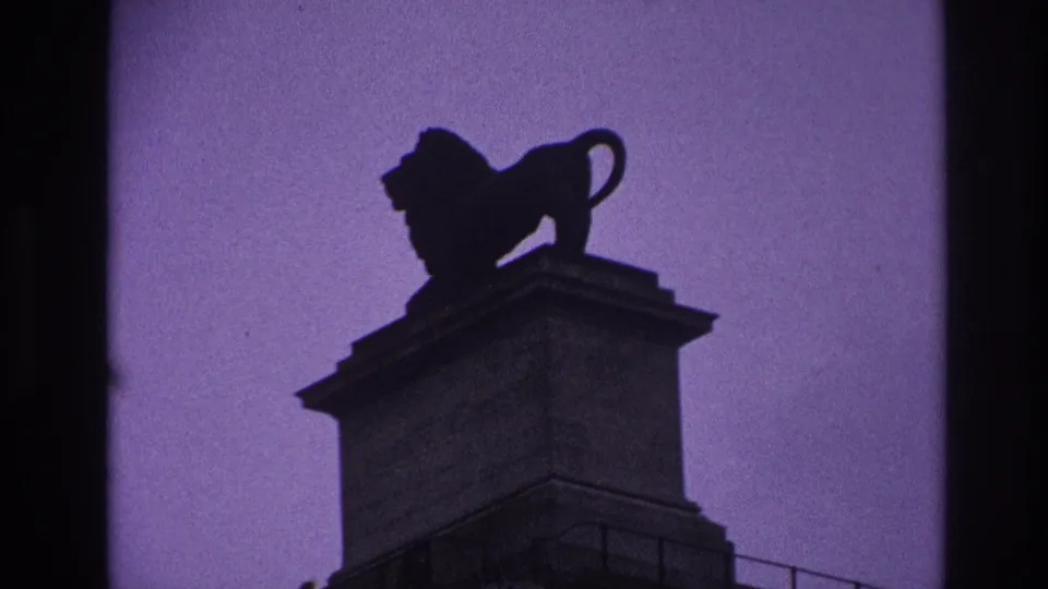 1967 Paris frame with the lion statue centered high on its pedestal, rendered as a dark silhouette against tinted sky.