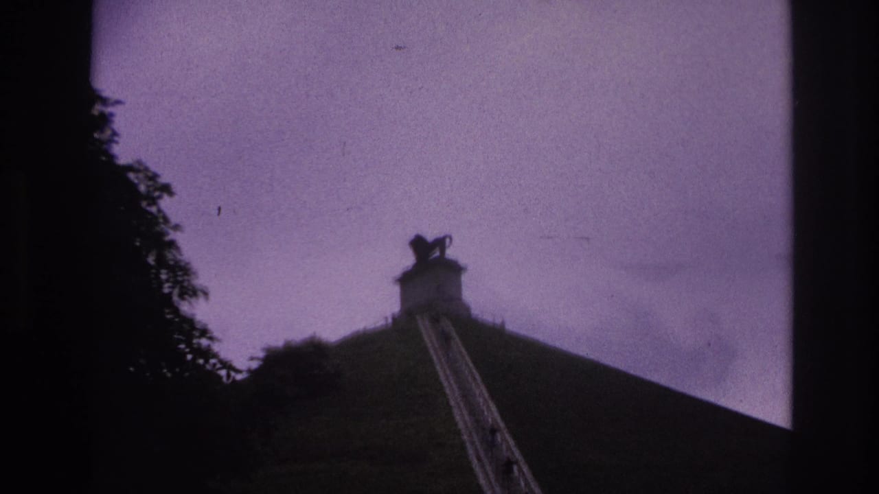 1967 Paris home-movie frame looking up a steep grassy slope and stone stairway toward a dark hilltop statue.