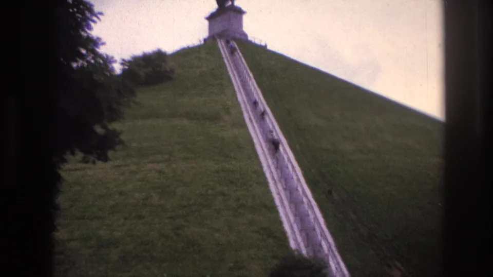 1967 Paris home-movie frame showing a long pale stairway with small visitors climbing toward a hilltop statue.