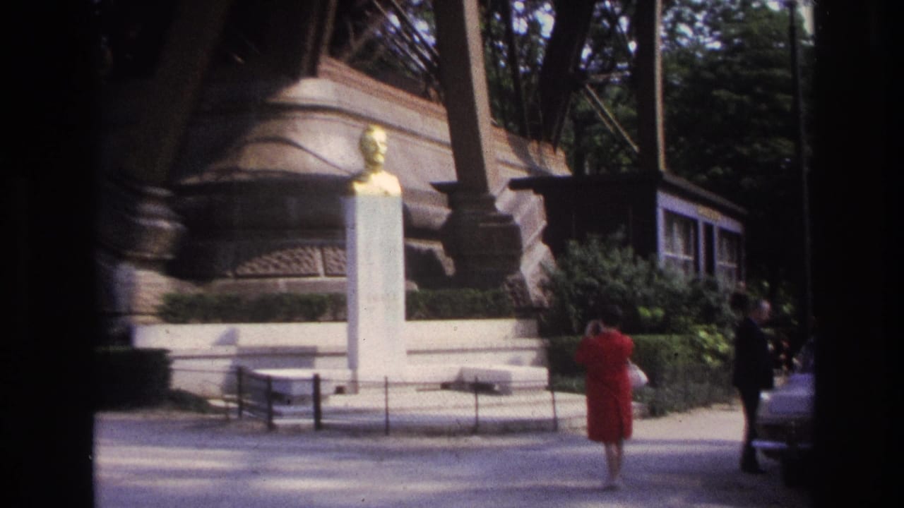 Woman in red dress and man near a white pedestal statue by Eiffel Tower structure.