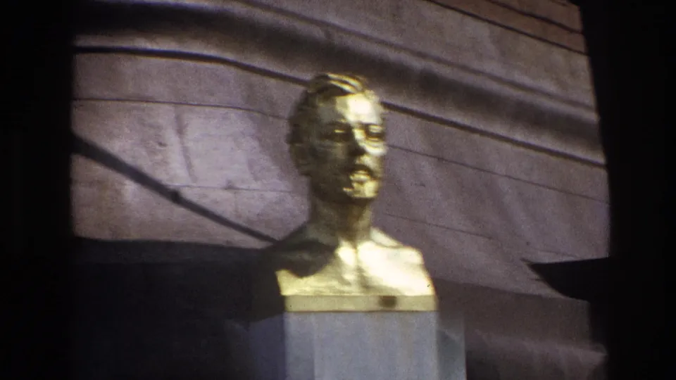 Tight 1967 Paris frame of the golden male bust, with its face and shoulders filling more of the home-movie composition.