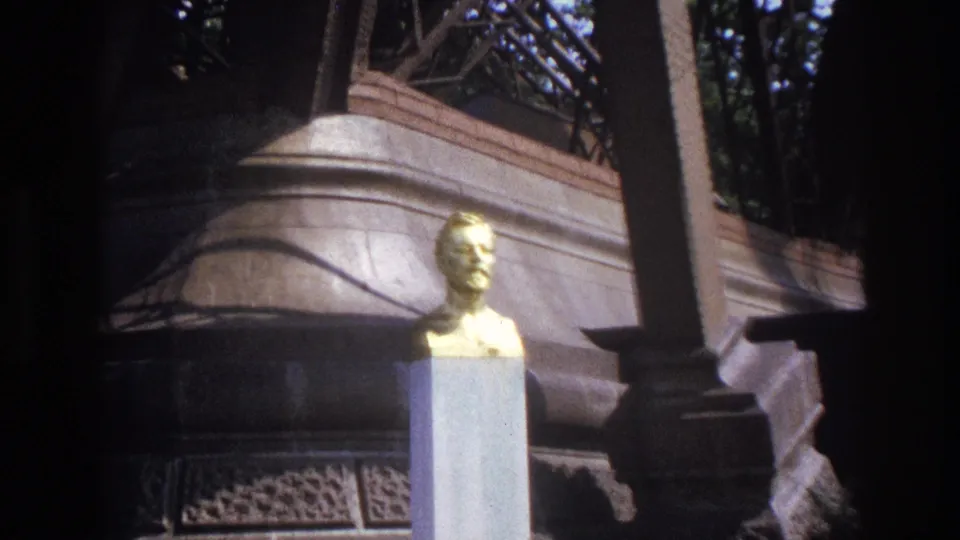 Wider 1967 Paris home-movie view of the gilded bust near columns, railings, masonry, and background greenery.