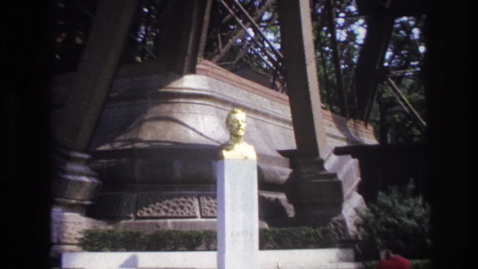 1967 Paris frame showing the gilded bust at right of center with columns, decorative stonework, railings, and shrubs around it.