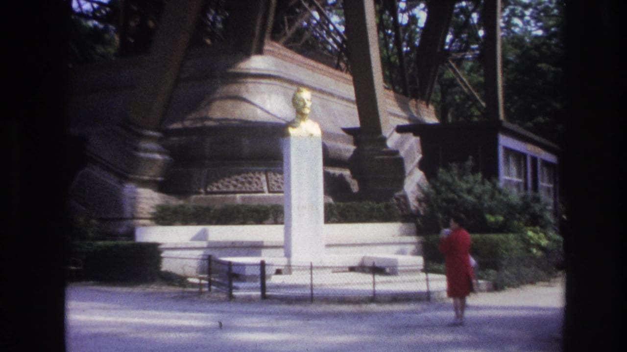 Woman in red walks away from a white monument with trees behind it.