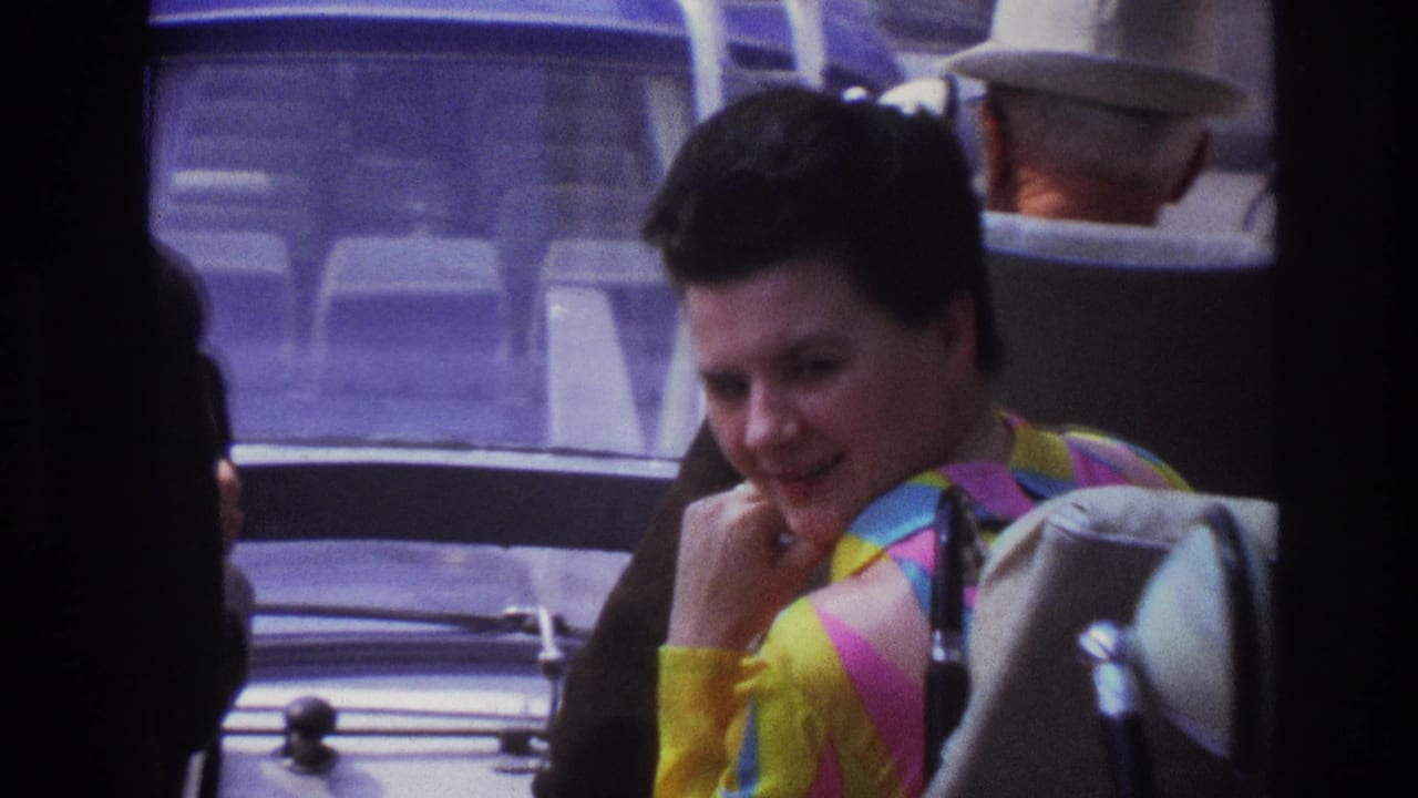 1967 Paris public-transport view of a smiling female passenger in a vivid striped shirt, with a man in a light hat behind her.