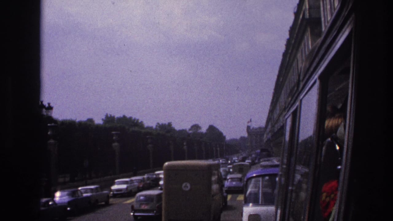 Congested lanes of older cars and a van beside a bus or coach window.